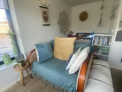 a living room with a blue couch with pillows at Houseboat Ark van Amstel in Amsterdam