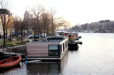 a house boat is docked on a river at Houseboat Ark van Amstel in Amsterdam