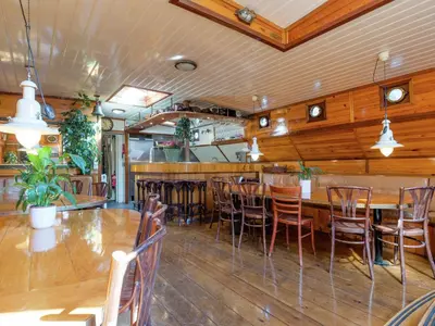a restaurant with a bar with wooden tables and chairs at Boat in Leiden near City Center & Museums in Leiden