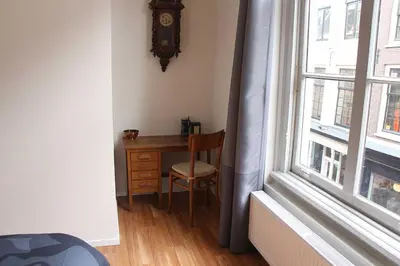 a desk with a chair next to a window with a clock at B&B Utrecht Domkwartier in Utrecht