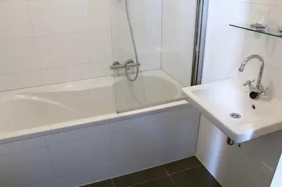 a white bathroom with a tub and a sink at B&B Utrecht Domkwartier in Utrecht