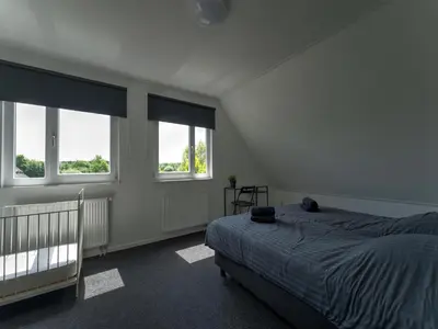 a bedroom with a bed and two windows at Villa in Zeewolde near Horsterwold Forest in Zeewolde