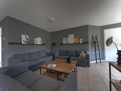 a living room with blue couches and a table at Villa in Zeewolde near Horsterwold Forest in Zeewolde