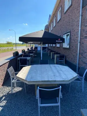 a table with chairs and an umbrella next to a building at Hotel de Keizerskroon Amsterdam-Schiphol-Halfweg in Halfweg