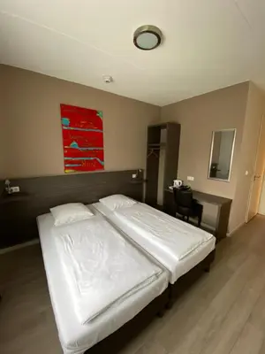 a bedroom with a white bed and a desk at Hotel de Keizerskroon Amsterdam-Schiphol-Halfweg in Halfweg