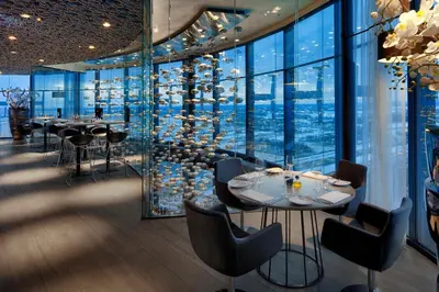 a restaurant with tables and chairs and large windows at Fletcher Hotel Amsterdam in Amsterdam