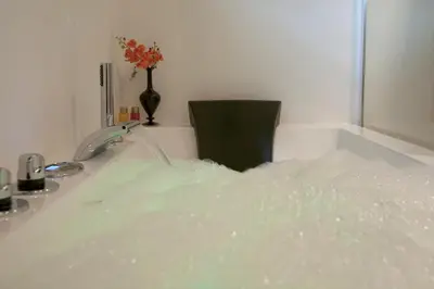 a bath tub filled with water next to a black chair at Design B&B Naarden Vesting in Naarden