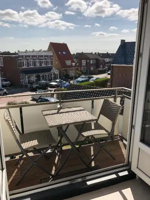 a balcony with a table and chairs on a balcony at By Simonis in Zandvoort