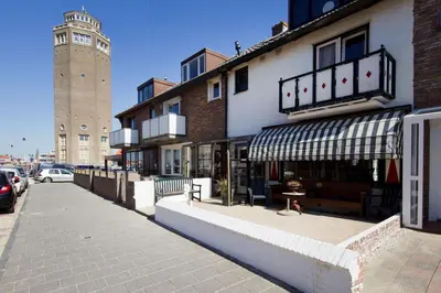 a building with a store with a clock tower in the background at By Simonis in Zandvoort