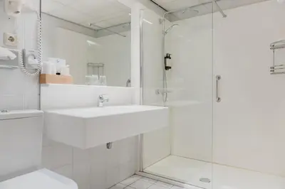 a white bathroom with a sink and a shower at Hotel Fita in Amsterdam