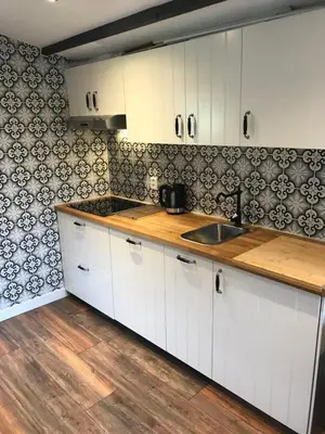 a kitchen with white cabinets and black and white tiles at Beach House Milou zandvoort Private Parking in Zandvoort