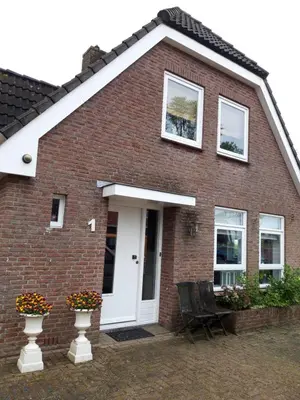 a brick house with a white door and windows at Gastenverblijf appartement tussen Alkmaar en Hoorn in Oterleek