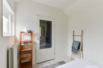 a white bedroom with a door and a mirror at Holiday Beach House in Zandvoort