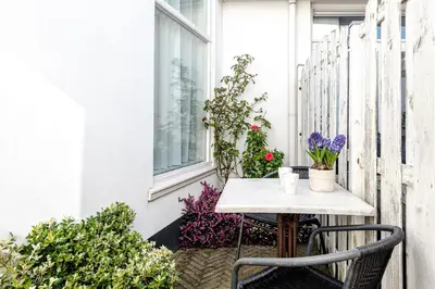 a small table and chairs on a balcony with flowers at BenSan Beach House in Zandvoort