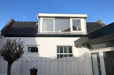 a white house with a white fence and a window at BenSan Beach House in Zandvoort