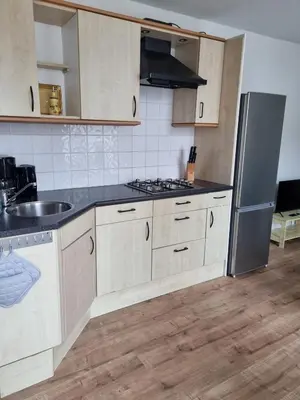 a kitchen with white cabinets and a stainless steel refrigerator at BenSan Beach House in Zandvoort