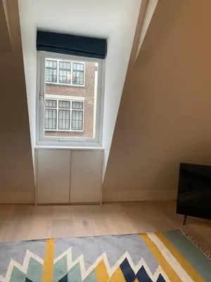 an attic room with a window and a rug at Kangaroom in Amsterdam