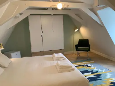 a attic bedroom with a bed and a chair at Kangaroom in Amsterdam