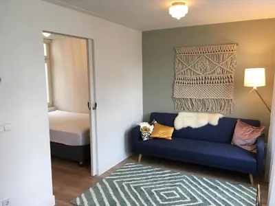 a living room with a blue couch and a bed at Kangaroom in Amsterdam