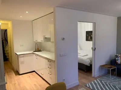 a kitchen with white cabinets and a bed in a room at Kangaroom in Amsterdam