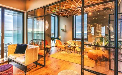 a living room with chairs and tables and windows at Four Elements Hotel in Amsterdam