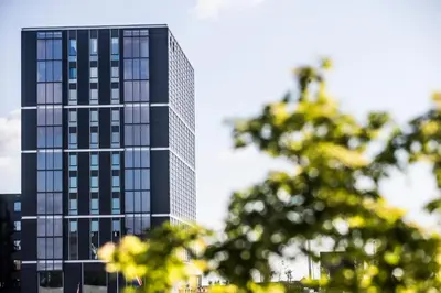 a tall black office building with glass windows at Four Elements Hotel in Amsterdam
