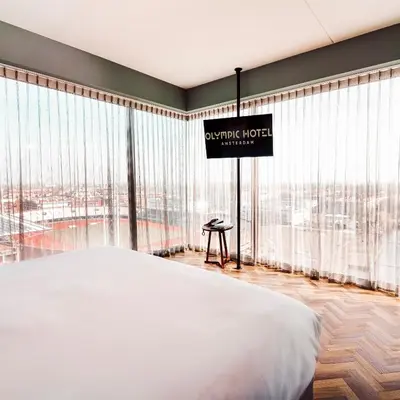 a hotel room with a large bed and large windows at Olympic Hotel in Amsterdam