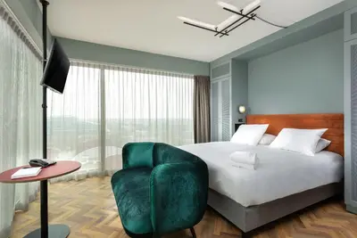 a bedroom with a large bed and a green chair at Olympic Hotel in Amsterdam
