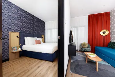 a hotel room with a bed and a blue couch at Citadines Sloterdijk Station Amsterdam in Amsterdam