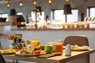 a table topped with plates of food and orange juice at Citadines Sloterdijk Station Amsterdam in Amsterdam
