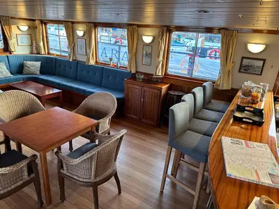 a restaurant with a blue couch and tables and chairs at Hotelboat Angeline in Amsterdam