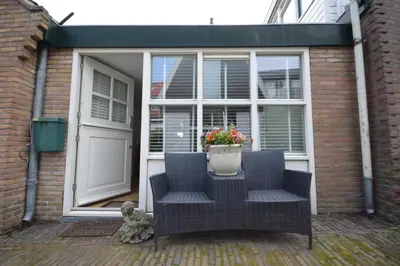 a patio with two chairs and a door with a plant at 't Duinhuisje in Zandvoort