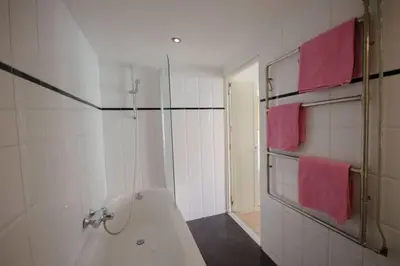 a bathroom with a bath tub and pink towels at 't Duinhuisje in Zandvoort