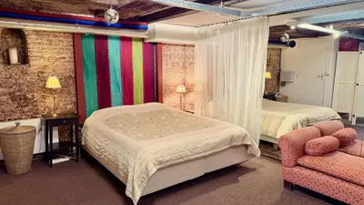 a bedroom with two beds and a chair at Top-notch apartment along canal in historic centre in Amsterdam