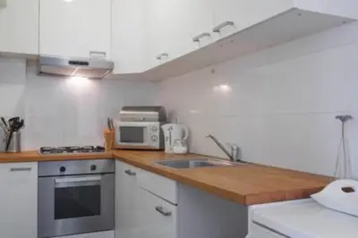 a white kitchen with a sink and a microwave at 't Zandhuisje in Zandvoort