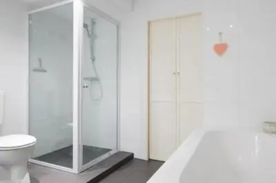 a bathroom with a glass shower and a toilet at 't Zandhuisje in Zandvoort
