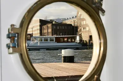 a mirror reflection of a boat in a canal at Sailor Suite Coaster Mado in Amsterdam