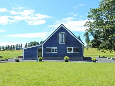 a blue house with a green lawn in front of it at UNESCO de Beemster, vakantiewoning in Noordbeemster
