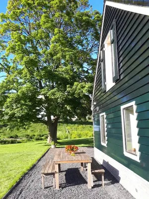 a picnic table next to a building with a tree at UNESCO de Beemster, vakantiewoning in Noordbeemster