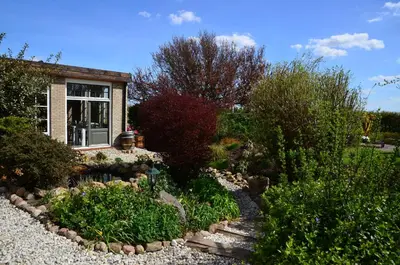 a garden with a house and some bushes and trees at Wellness Bed & Breakfast Pergamo in Voorhout