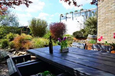 a wooden table with a bottle of wine and flowers on it at Wellness Bed & Breakfast Pergamo in Voorhout