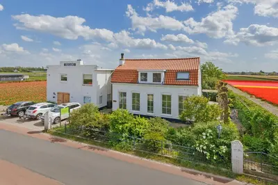 a house in a field of red tulips at Wellness Bed & Breakfast Pergamo in Voorhout