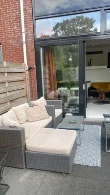 a wicker couch and a table on a patio at Canal Garden Apartment StayWell Amsterdam in Amsterdam