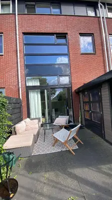 a patio with a couch and chairs in front of a building at Canal Garden Apartment StayWell Amsterdam in Amsterdam