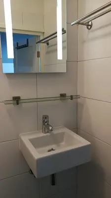 a bathroom with a white sink and a mirror at Canal Garden Apartment StayWell Amsterdam in Amsterdam