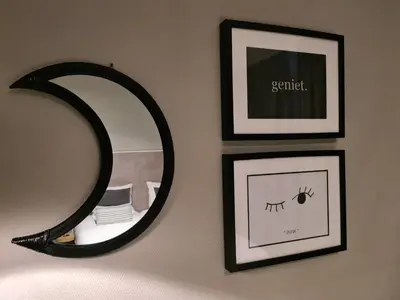 a mirror on a wall with two pictures and a frame at The BLOOM in Noordwijk aan Zee