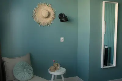 a room with a blue wall with a chair and a table at The BLOOM in Noordwijk aan Zee