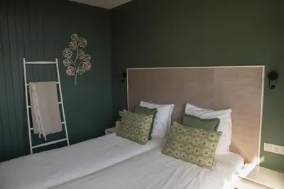 a bedroom with a bed with white sheets and green walls at The BLOOM in Noordwijk aan Zee