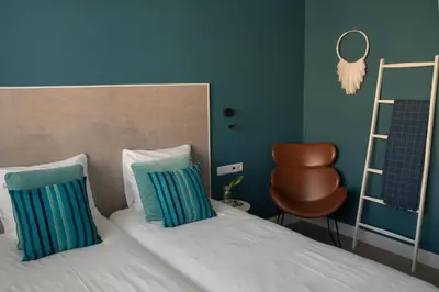 a bedroom with a bed with two pillows and a chair at The BLOOM in Noordwijk aan Zee