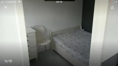 a small bedroom with a bed and a chair at Vakantiehuis Lara in Warmenhuizen